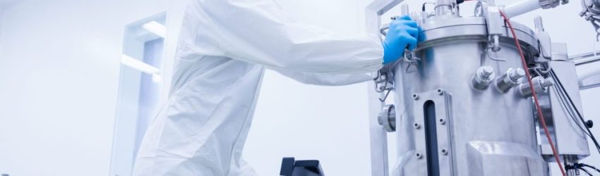 Scientist in protective suit standing on ladder in the factory